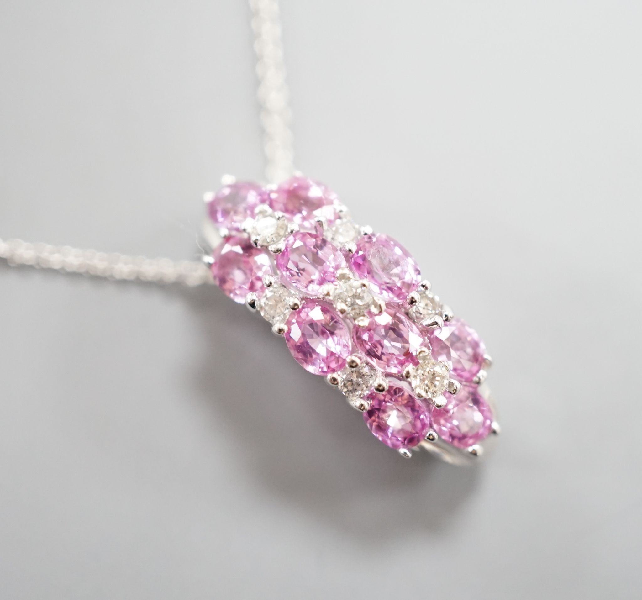 A modern 14k white metal pink sapphire and diamond cluster set pendant, on a 14k fine link chain(knotted)